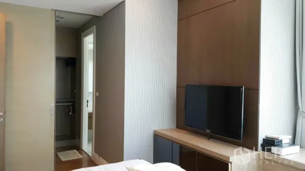 公寓 出租在Khlong Toei, Bangkok - 卧室内带电视柜、嵌入式衣柜与通往浴室的门，温馨明亮。