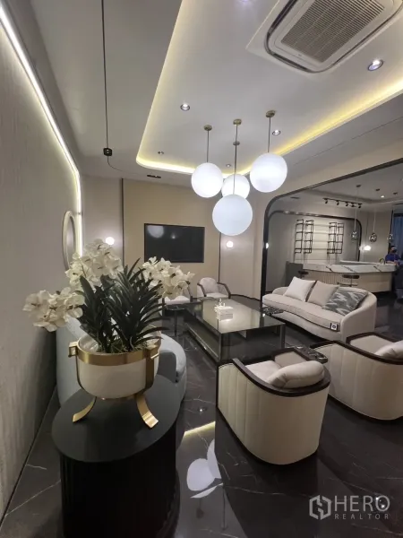 零售空间 出租 - 休息区配沙发与扶手椅，球形吊灯与隐藏灯槽天花。