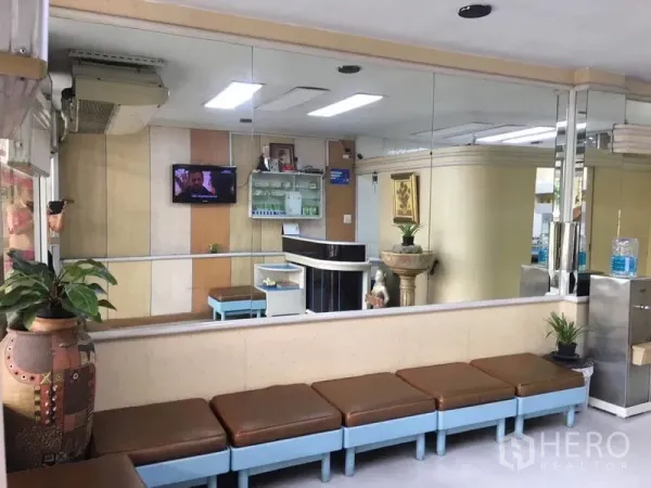 店屋 出租在Phra Khanong, Bangkok - 接待区配长椅、整面镜墙、盆栽与明亮顶灯。