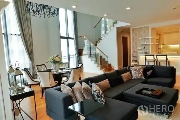 คอนโด ให้เช่าในKhlong Toei, Bangkok - ห้องนั่งเล่นเพดานสูงของคอนโดหรู โซฟาตัวยาว มุมทานอาหาร บันไดกระจก และครัวพร้อมเคาน์เตอร์บาร์