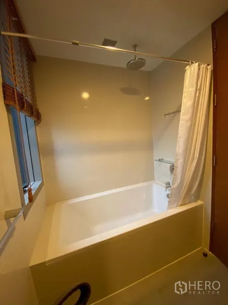 公寓 出租在Khlong Toei, Bangkok - 浴室设深浴缸、顶喷花洒与带百叶窗的窗户。