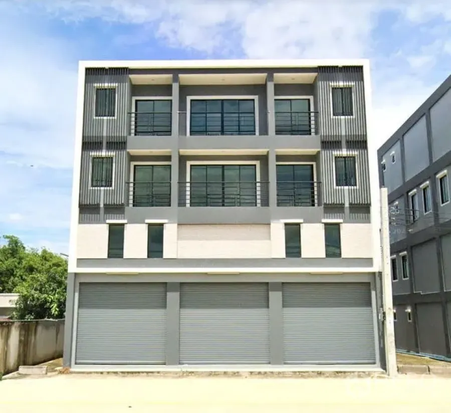 Warehouse for rent or sale in Nong Chok, Bangkok - Modern three-storey commercial building façade with balconies and multiple roller shutters.