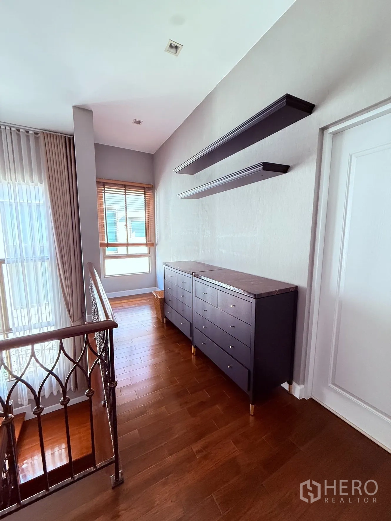 บ้านเดี่ยว for rent or sale in Prawet, Bangkok - โถงบันไดชั้นบนพื้นไม้ ราวเหล็กลาย และตู้ลิ้นชักกับชั้นวางติดผนัง.