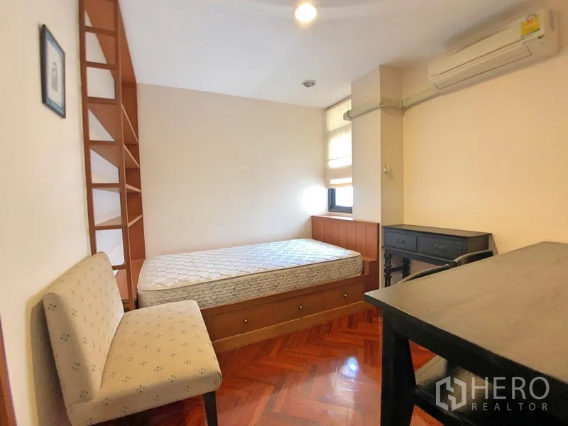 公寓 出租在Bang Rak, Bangkok - 次卧带单人床、抽屉收纳、书桌、梯形书架与空调。