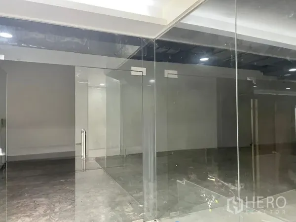 零售空间 出租在Khlong Toei, Bangkok - 近距离展示透明玻璃入口与门面墙体，通往室内。