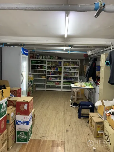 零售空间 出租在Sathon, Bangkok - 库房陈列饮料冰柜、金属货架及纸箱，木纹地面。