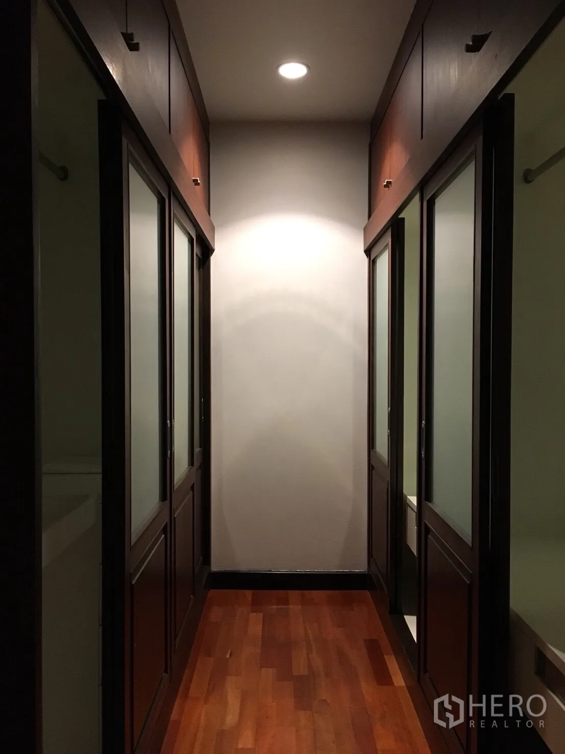 Condominium for rent in Watthana, Bangkok - Walk-in closet hallway with sliding wardrobe doors, recessed lighting, and wood floors.