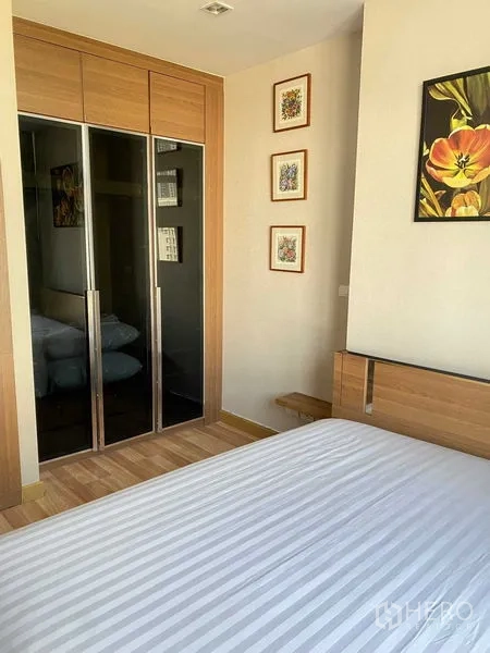 Condominium for rent in Phra Khanong, Bangkok - Bedroom with built-in sliding-door wardrobe, wood finishes and artwork.