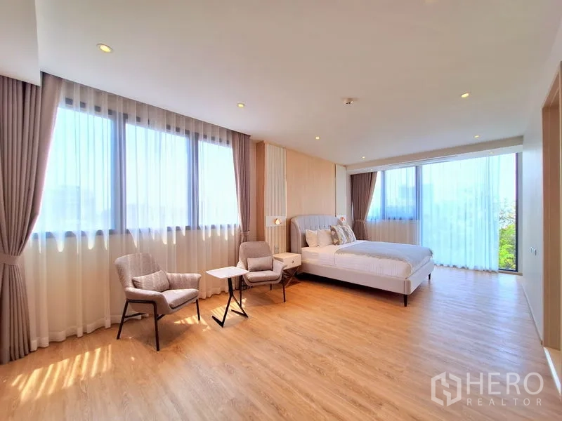 อพาร์ทเมนท์ ให้เช่าในBang Na, Bangkok - ห้องนอนที่สองขนาดใหญ่ มีเก้าอี้เอนกายข้างหน้าต่างพาโนรามาและพื้นไม้