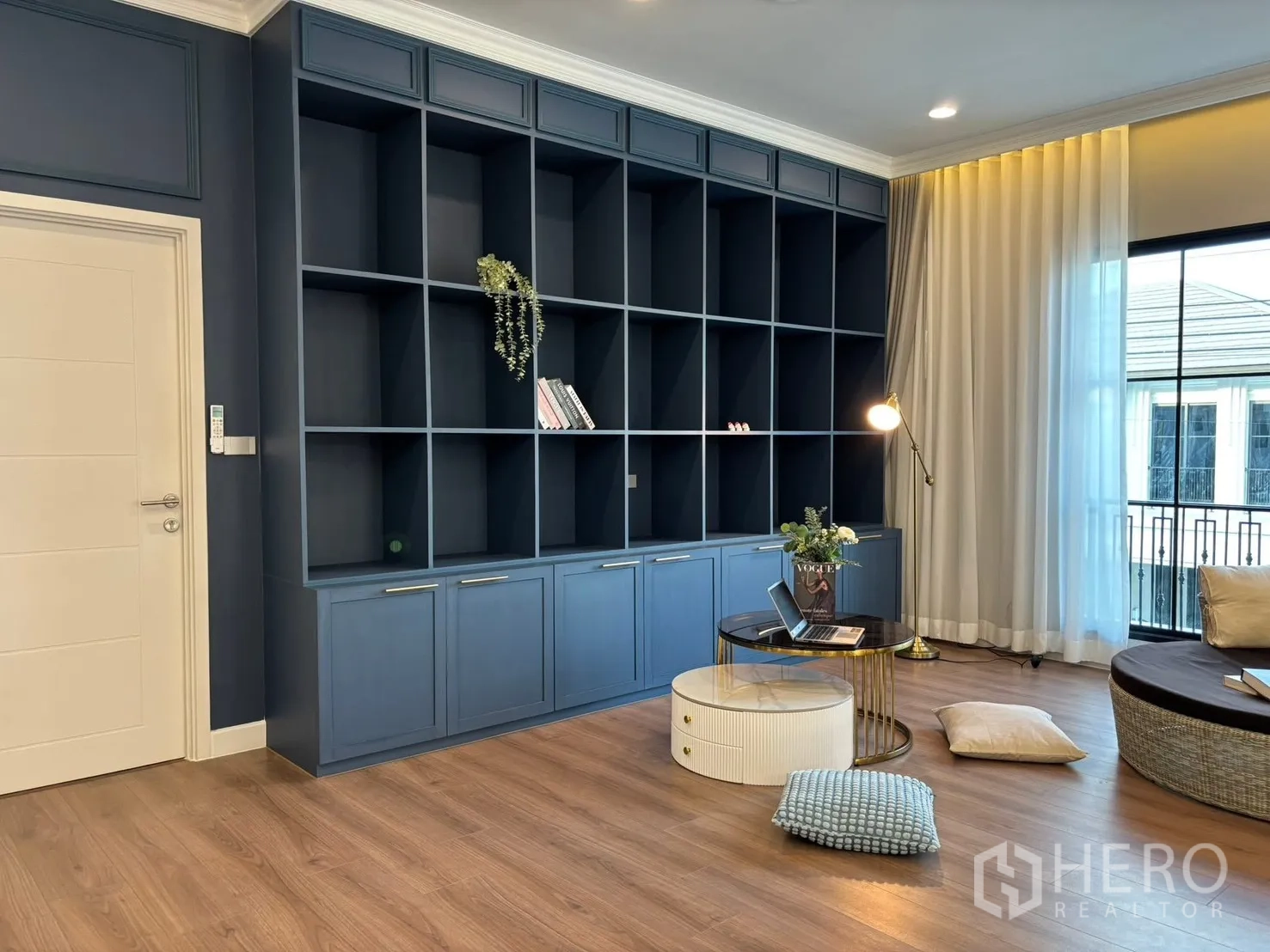 独立式住宅 出租在Bang Phli, Samut Prakan - 二层家庭活动室，整面蓝色书柜与阳台景观。