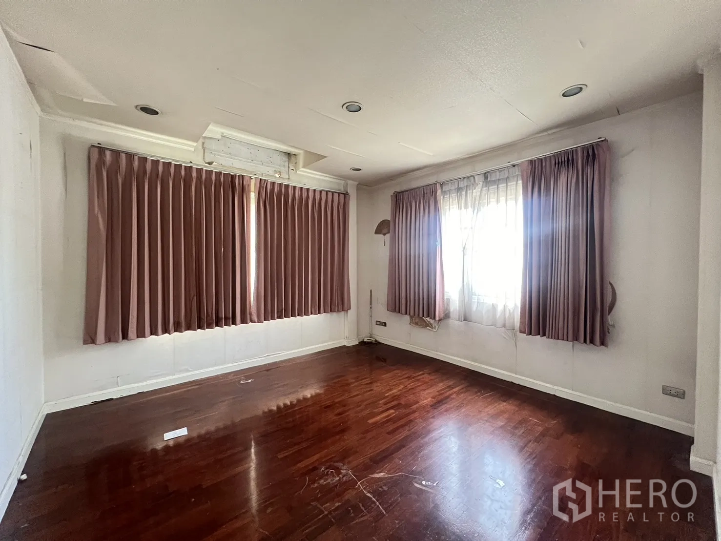 Detached House for sale in Saphan Sung, Bangkok - Room with polished wood floor and pink curtains on two windows.