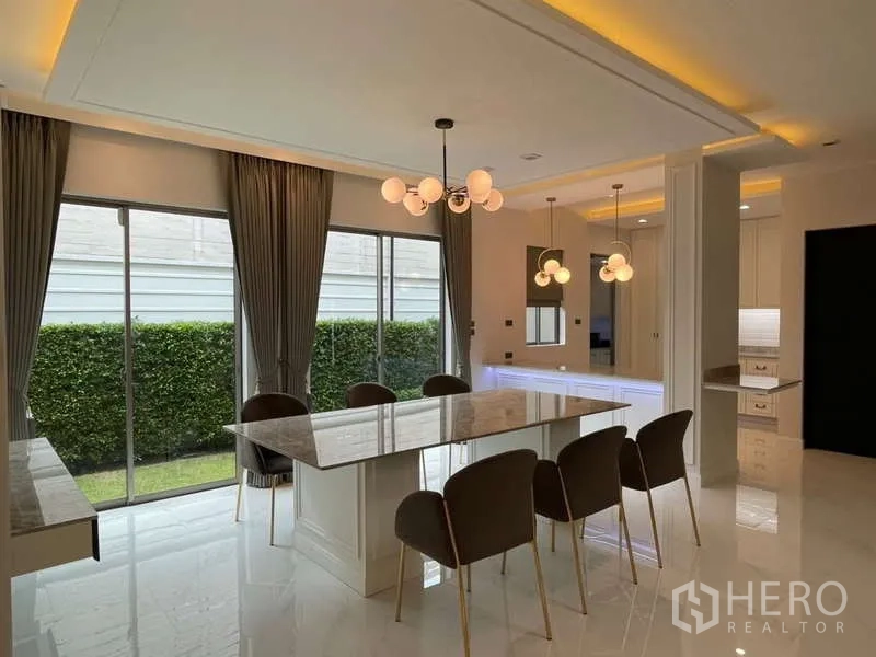 บ้าน ให้เช่าหรือขายในLat Krabang, Bangkok - พื้นที่รับประทานอาหารโต๊ะหินอ่อน เก้าอี้หกที่นั่ง และประตูกระจกเปิดสู่สวน