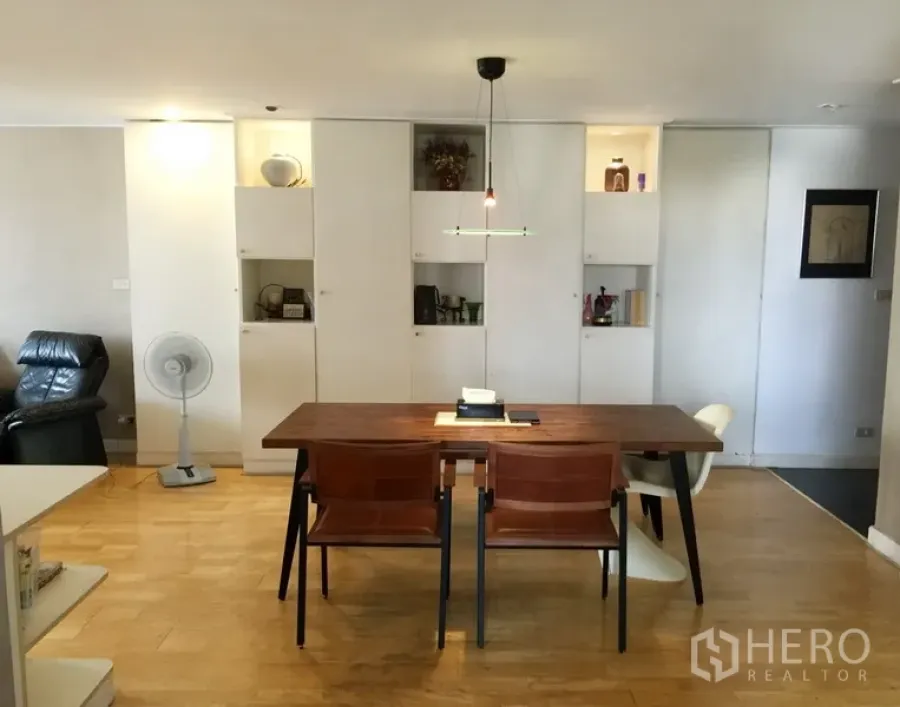 公寓 出租或出售在Watthana, Bangkok - 明亮餐区，木质餐桌与白色嵌入式柜体，曼谷公寓内景。