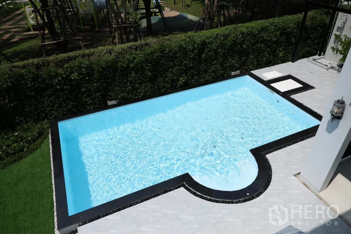 Detached House for rent or sale in Saphan Sung, Bangkok - Aerial view of turquoise private pool bordered by hedge and light-toned terrace.