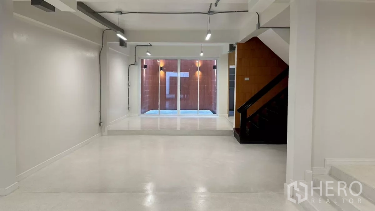 Home Office for rent in Watthana, Bangkok - Open-plan ground floor workspace facing a lightwell patio through large glass doors.