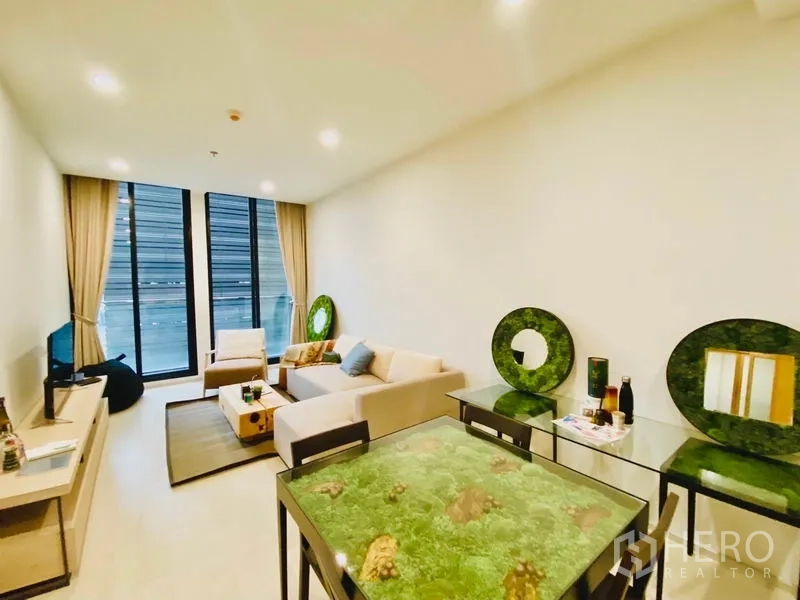 คอนโด ให้เช่าในPathum Wan, Bangkok - มุมห้องนั่งเล่นมองไปยังหน้าต่างบานสูง และโต๊ะทานข้าวลายมอสสีเขียว