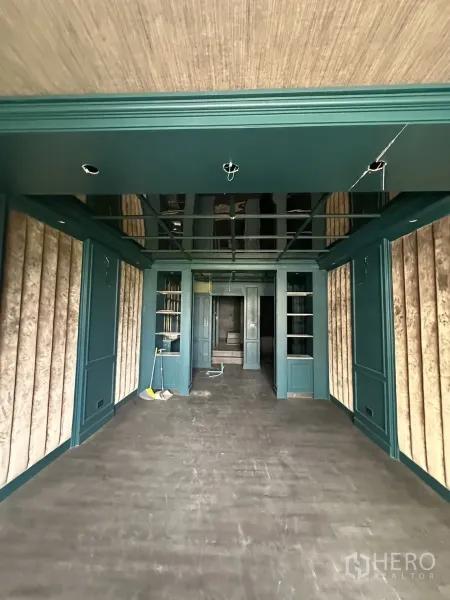 店屋 出租在Watthana, Bangkok - 一层开放式零售空间，墨绿色墙板与展示搁架。