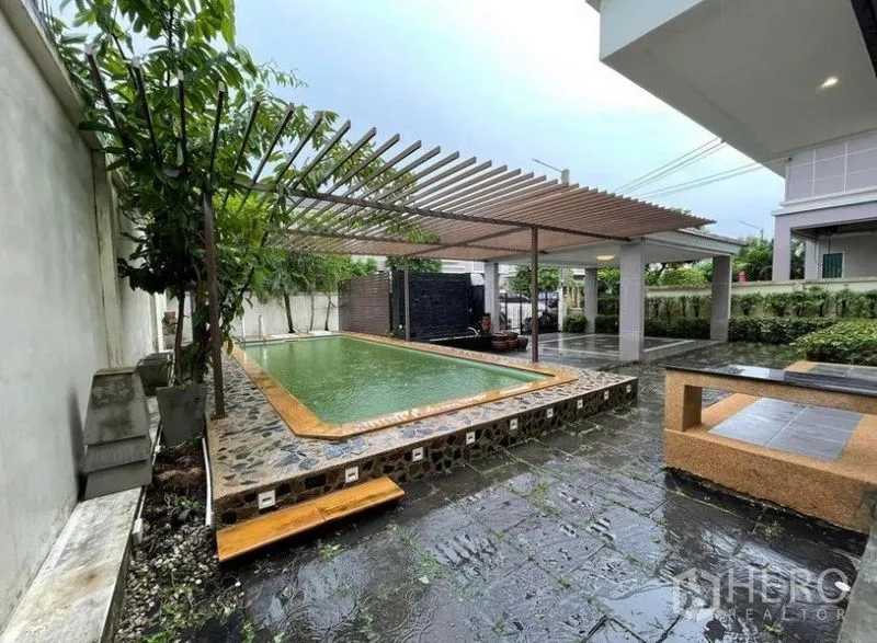独立式住宅 出售在Bang Phli, Samut Prakan - 私人泳池配格栅遮阳棚、石材露台与绿意围篱。