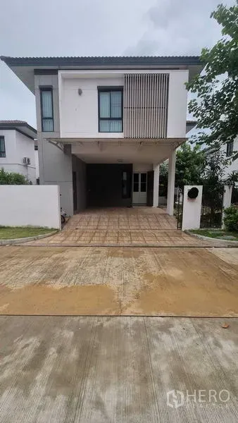 Detached House for rent in Bang Khun Thian, Bangkok - Modern two-storey detached house with a covered two-car carport, tiled driveway and vertical wood screen facade.