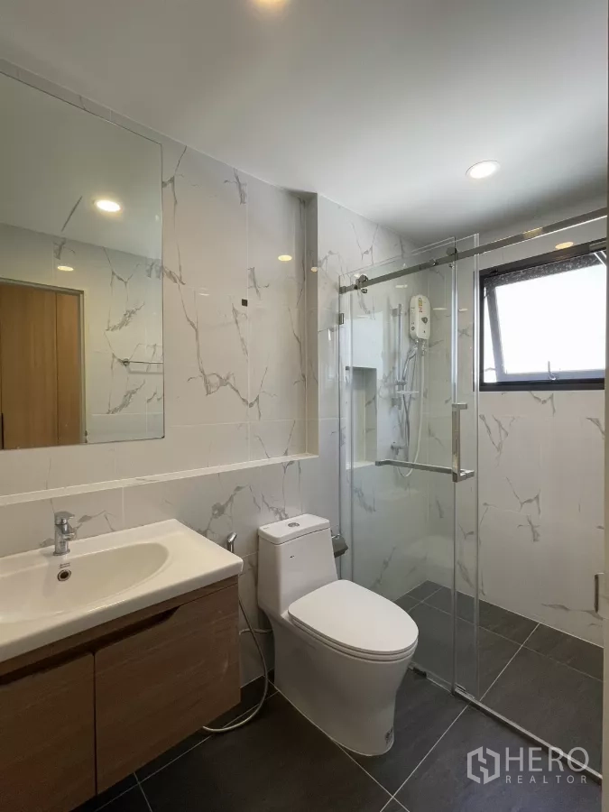 Detached House for rent in Bang Phli, Samut Prakan - Modern bathroom with glass shower, marble-look tiles and vanity.