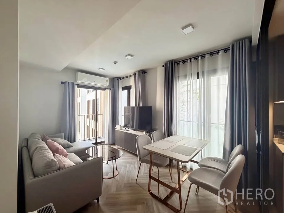 公寓 for rent in Watthana, Bangkok - 采光明亮的客厅，带阳台门、电视柜、圆形茶几和餐桌椅。