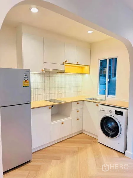 ทาวน์เฮาส์ ให้เช่าในSuan Luang, Bangkok - ครัวรูปตัวแอล โทนขาว พร้อมตู้เก็บของ ผนังกระเบื้อง ตู้เย็น อ่างล้างจาน และเครื่องซักผ้า