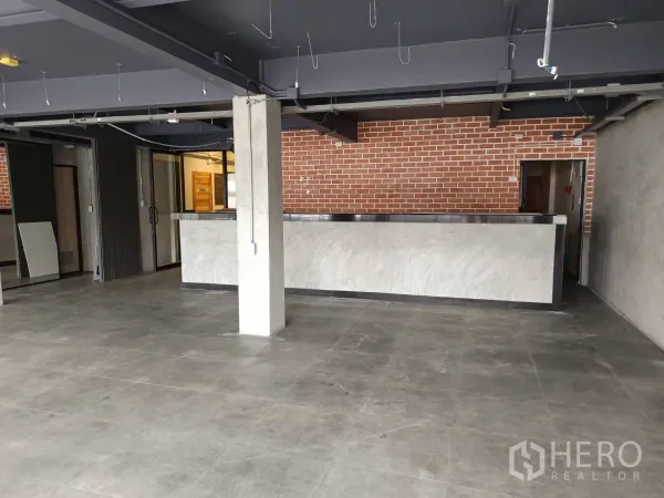 零售空间 出租在Watthana, Bangkok - 开放式零售室内，水泥地面、长吧台与红砖特色墙。