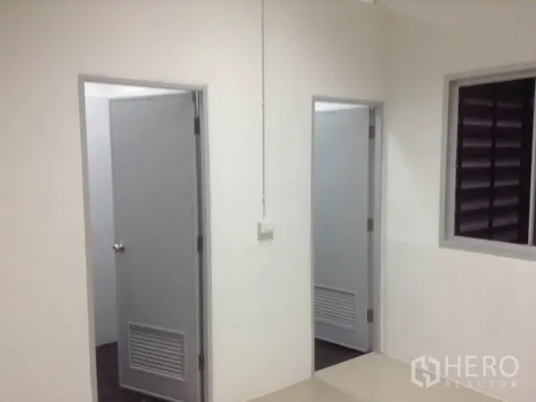 คลังสินค้า ให้เช่าในBang Kapi, Bangkok - โถงทางเดินมีประตูสีเทา 2 บานไปยังห้องน้ำและห้องอเนกประสงค์ พร้อมหน้าต่างระบายอากาศ