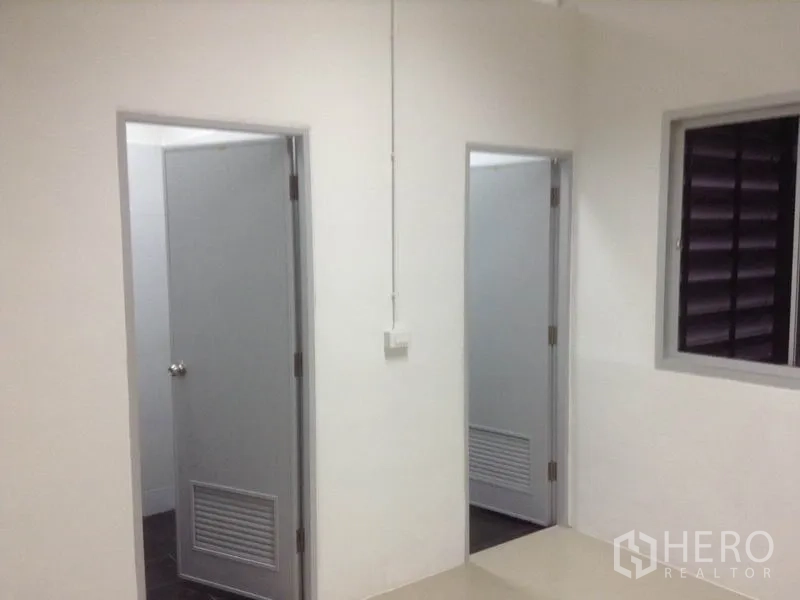 คลังสินค้า ให้เช่าในBang Kapi, Bangkok - โถงทางเดินมีประตูสีเทา 2 บานไปยังห้องน้ำและห้องอเนกประสงค์ พร้อมหน้าต่างระบายอากาศ