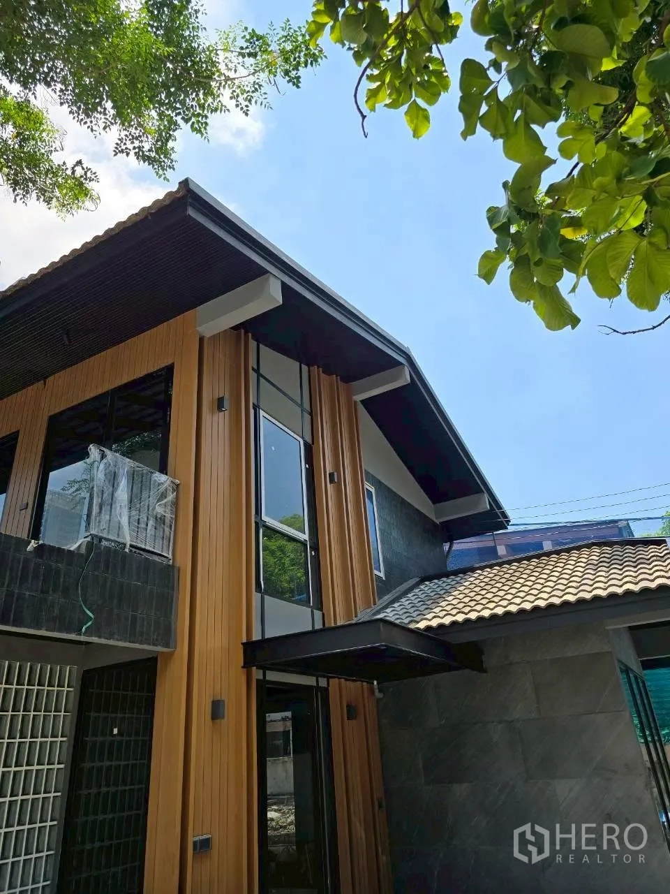 Detached House for rent in Phra Khanong, Bangkok - Modern two-story house exterior with wood-look cladding and tall windows.