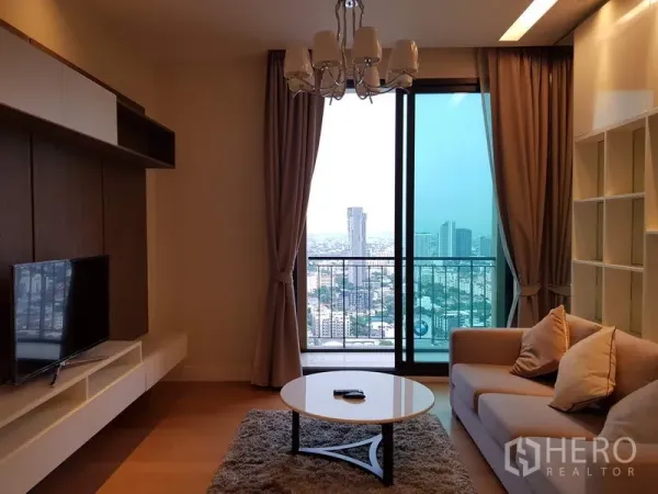 คอนโด ให้เช่าในChatuchak, Bangkok - ห้องนั่งเล่นมีโซฟา โคมระย้า และระเบียงชมวิวสกายไลน์กรุงเทพฯ