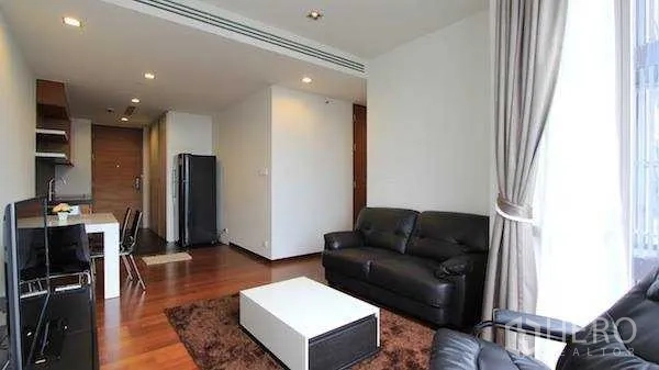 Condominium for rent - Open‑plan living area facing kitchenette and entry, with leather seating and large windows.