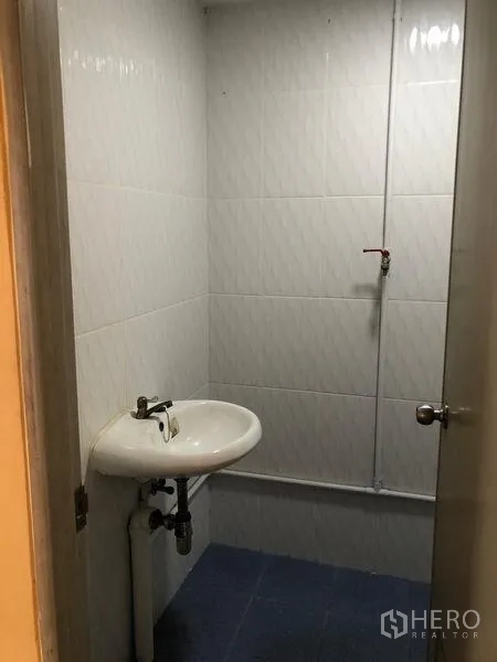Warehouse for rent in Pak Kret, Nonthaburi - Compact washroom with white wall tiles and a wall-mounted sink.