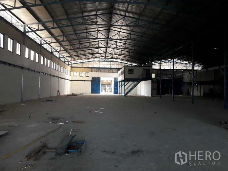 คลังสินค้า ให้เช่าในMueang Samut Prakan, Samut Prakan - มุมมองภายในโกดัง เห็นประตูโหลดสีน้ำเงิน ช่องแสงยาว และออฟฟิศชั้นลอย