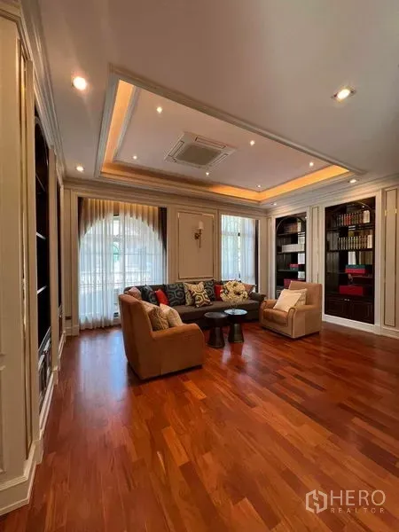 Detached House for rent or sale in Thawi Watthana, Bangkok - Cozy family lounge with recessed ceiling, built-in shelves and warm wood flooring.