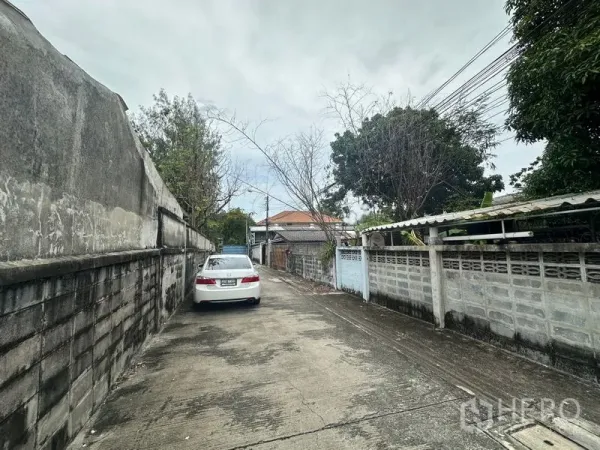 ที่ดิน ขายในPhra Khanong, Bangkok - ซอยคอนกรีตแคบแบบพักอาศัย มีกำแพงรั้วสูง รถสีขาวจอด และสายไฟพาดเหนือถนน