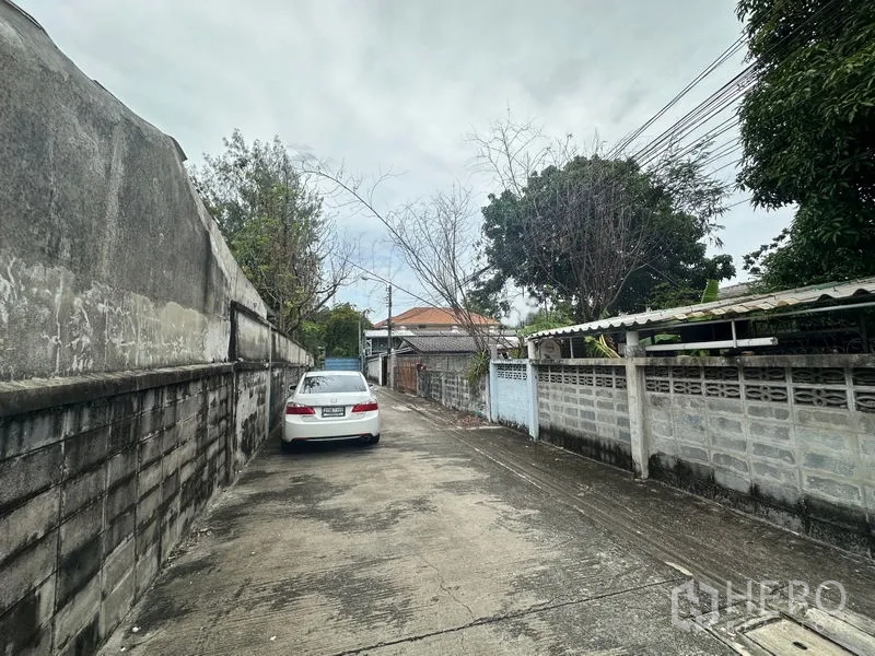 ที่ดิน ขายในPhra Khanong, Bangkok - ซอยคอนกรีตแคบแบบพักอาศัย มีกำแพงรั้วสูง รถสีขาวจอด และสายไฟพาดเหนือถนน