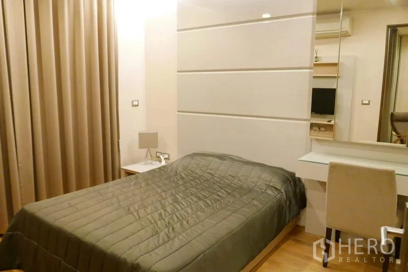 Condominium for rent in Ratchathewi, Bangkok - Warm bedroom with a double bed, padded headboard panels, full curtains and a built-in desk.