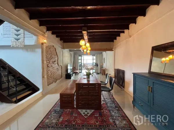 Townhouse for rent in Ratchathewi, Bangkok - Elongated dining hall with beamed ceiling, staircase and windowed lounge at the far end.