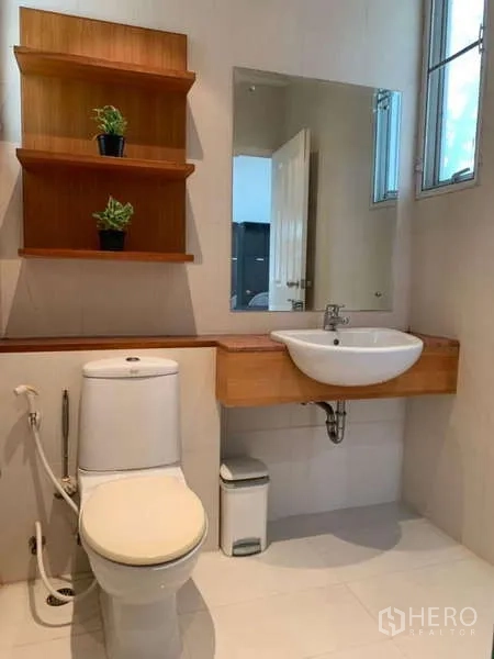 独立式住宅 出租在Lat Krabang, Bangkok - 客卫设墙面置物架、梳妆镜与白色台盆。