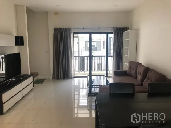 Townhouse for rent in Saphan Sung, Bangkok - Bright lounge with large windows, balcony access and glossy tiled floors.