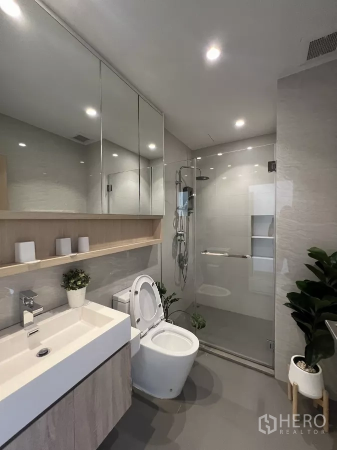 Condominium for rent or sale in Chatuchak, Bangkok - Bathroom with toilet, mirrored cabinets, rain shower and built‑in shelving.