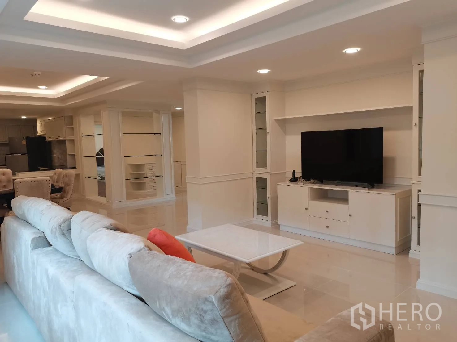 Condominium for rent in Watthana, Bangkok - Living area with sectional sofa, TV unit, and view toward the kitchen and dining.