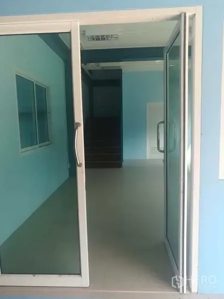 工厂 出售在Sai Noi, Nonthaburi - 玻璃推拉门入口通向办公室区域，可见楼梯。