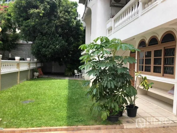 独立式住宅 出租在Watthana, Bangkok - 房屋一侧的草坪花园，成树与拱形窗相映。