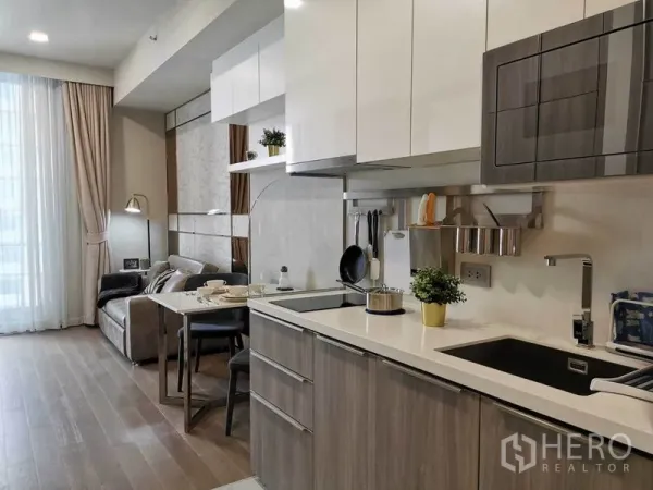 Condominium for rent in Watthana, Bangkok - Open-plan kitchen and living room with white cabinetry, dining set, and floor-to-ceiling window in a modern Asoke condo.