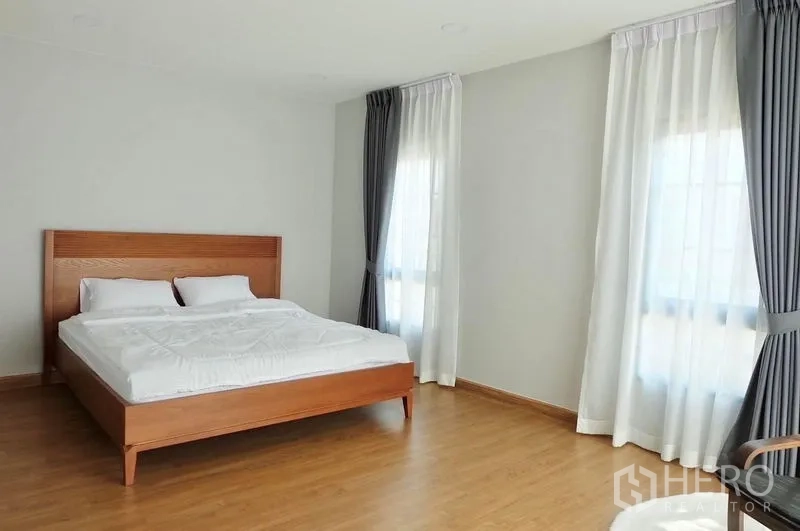 Detached House for rent in Bang Phli, Samut Prakan - Spacious master bedroom with wood bedframe, corner windows and laminate flooring.