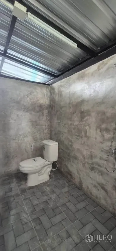 Warehouse for rent in Lat Phrao, Bangkok - Alternate view of the bathroom showing toilet and shower against rendered walls.