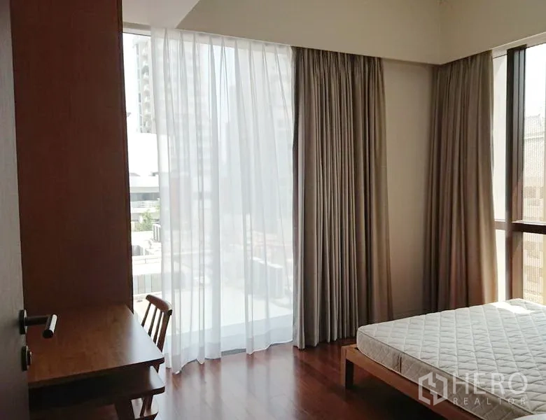 คอนโด ขายในPathum Wan, Bangkok - ห้องนอนมุมอาคาร หน้าต่างบานใหญ่ ผ้าม่านโปร่ง พร้อมโต๊ะทำงานและเตียง