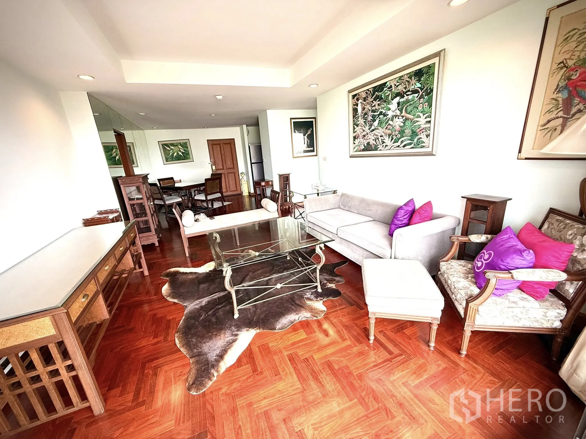 Condominium for rent in Sathon, Bangkok - Living room with balcony access, glass tables and decorative artwork.